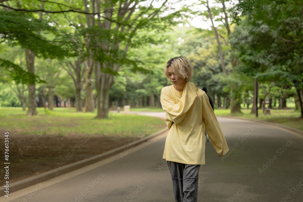 In early summer, a Japanese man in his twenties wearing yellow clothes, walking and strolling through Yoyogi Park, Shibuya, Tokyo, during the day. In early summer, a Japanese man in his twenties wearing yellow clothes, walking and strolling through Yoyogi Park, Shibuya, Tokyo, during the day.