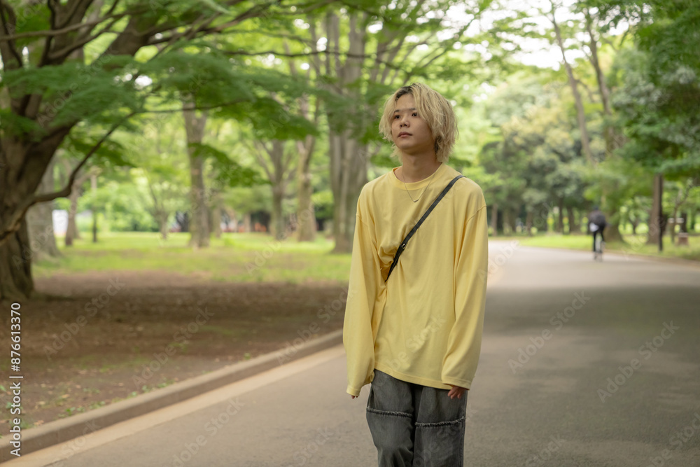 In early summer, a Japanese man in his twenties wearing yellow clothes, walking and strolling through Yoyogi Park, Shibuya, Tokyo, during the day. In early summer, a Japanese man in his twenties wearing yellow clothes, walking and strolling through Yoyogi Park, Shibuya, Tokyo, during the day.