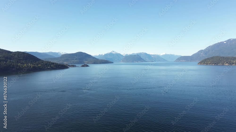 Flying over Coastline Surrounded by Forested Hills and Snow-Capped Mountains Under a Clear Sky Flying over Coastline Surrounded by Forested Hills and Snow-Capped Mountains Under a Clear Sky