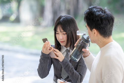 In March, a Taiwanese woman in her twenties and a Hong Kong man are taking a break in a park in Zhongzheng District, Taipei City, Taiwan, eating snacks and drinking water. photo