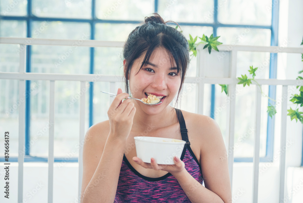Asian women eating cereal oatmeal with milk organic nutrition ingredients. Women hands holding spoon and bowl with healthy dairy product cereal, fruits, banana. Dietary healthy lifestyle at home Asian women eating cereal oatmeal with milk organic nutrition ingredients. Women hands holding spoon and bowl with healthy dairy product cereal, fruits, banana. Dietary healthy lifestyle at home