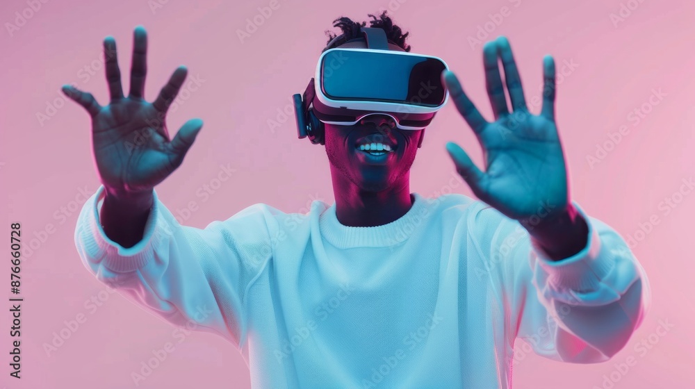 Smiling African man in white sweater over pink gradient background using virtual reality headset for smartphone, playing video games Smiling African man in white sweater over pink gradient background using virtual reality headset for smartphone, playing video games