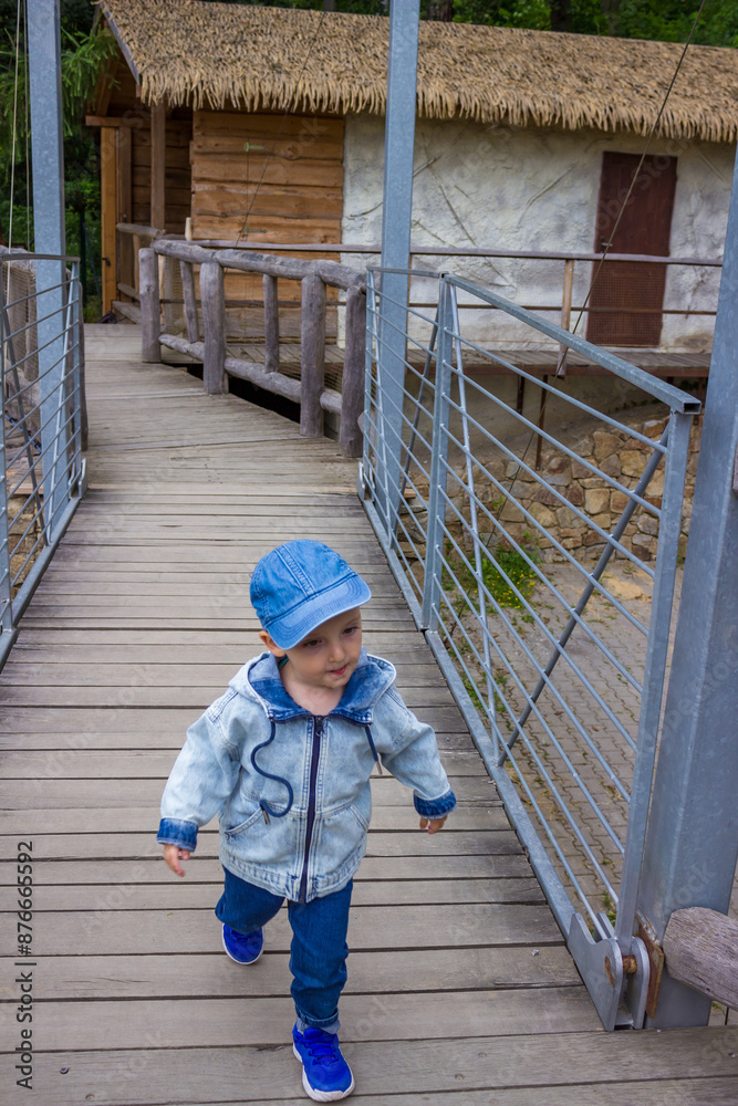 A little toddler in jeans has fun watching the animals at a modern urban zoo A little toddler in jeans has fun watching the animals at a modern urban zoo