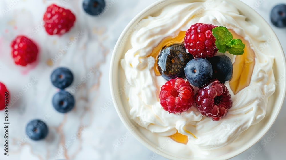 Yogurt topped with fresh berries and honey, surrounded by blueberries and raspberries on a marble surface. Yogurt topped with fresh berries and honey, surrounded by blueberries and raspberries on a marble surface.