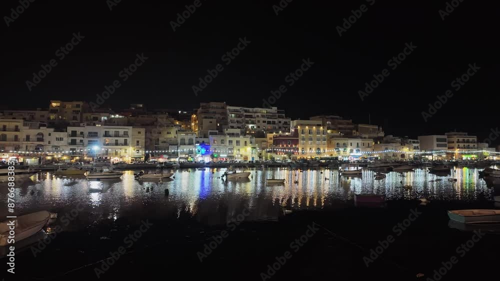 Evening view of the town center of Marsaskala across the Mediterranean bay full of boats with the illuminated promenade and restaurants in the background in Malta. Evening view of the town center of Marsaskala across the Mediterranean bay full of boats with the illuminated promenade and restaurants in the background in Malta.