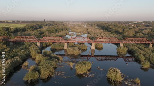 Old railroad bridge over the seasonal Komati River in South Africa, early morning golden light. Aerial wide shot. photo