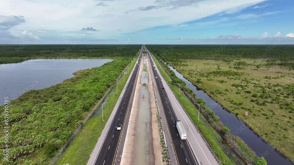 Rising drone shot showing traffic on highway Alley of Everglades in Florida,USA. Marshland vegetated landscape in America. Rising drone shot showing traffic on highway Alley of Everglades in Florida,USA. Marshland vegetated landscape in America.