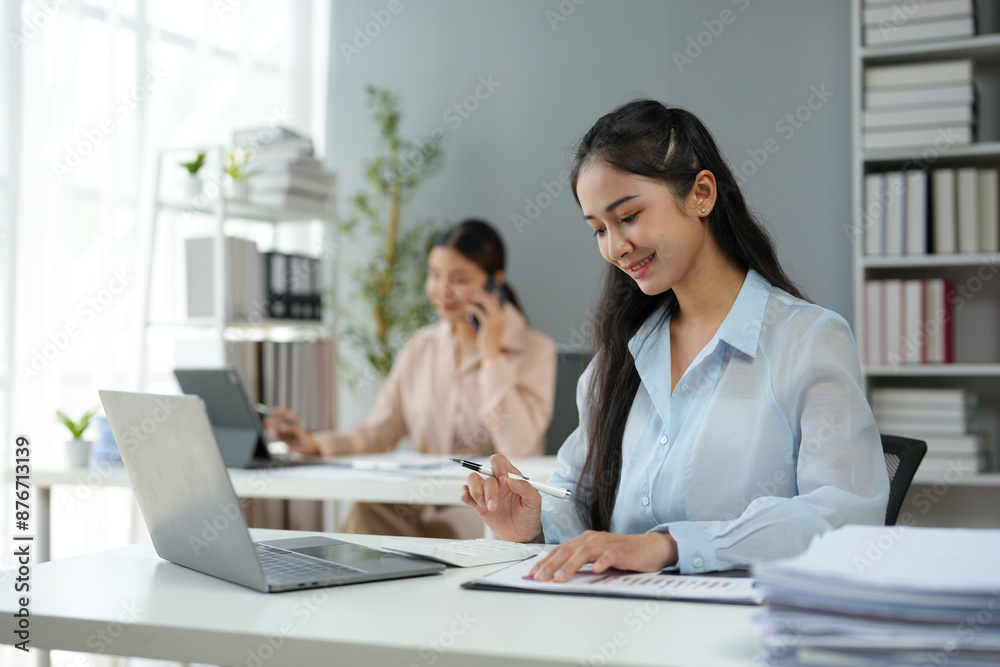 Attractive Asian businesswoman sitting with laptop computer and financial documents Business planning, home office, report, calculation, balance, document, graph, chart, online marketing. Attractive Asian businesswoman sitting with laptop computer and financial documents Business planning, home office, report, calculation, balance, document, graph, chart, online marketing.