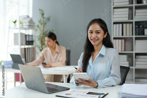 Asian businesswoman works on laptop and calculates with financial calculator from graphs, statistics, charts. Planning. Business success results in modern office.