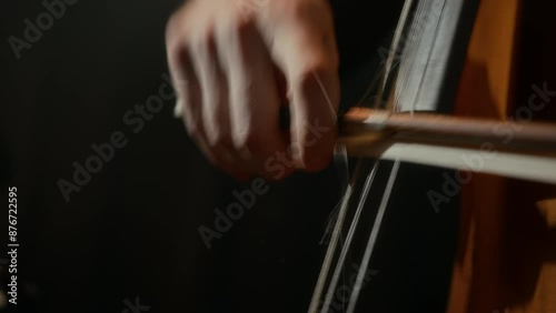 Closeup of unrecognizable male cellist playing his instrument virtuously on black background photo