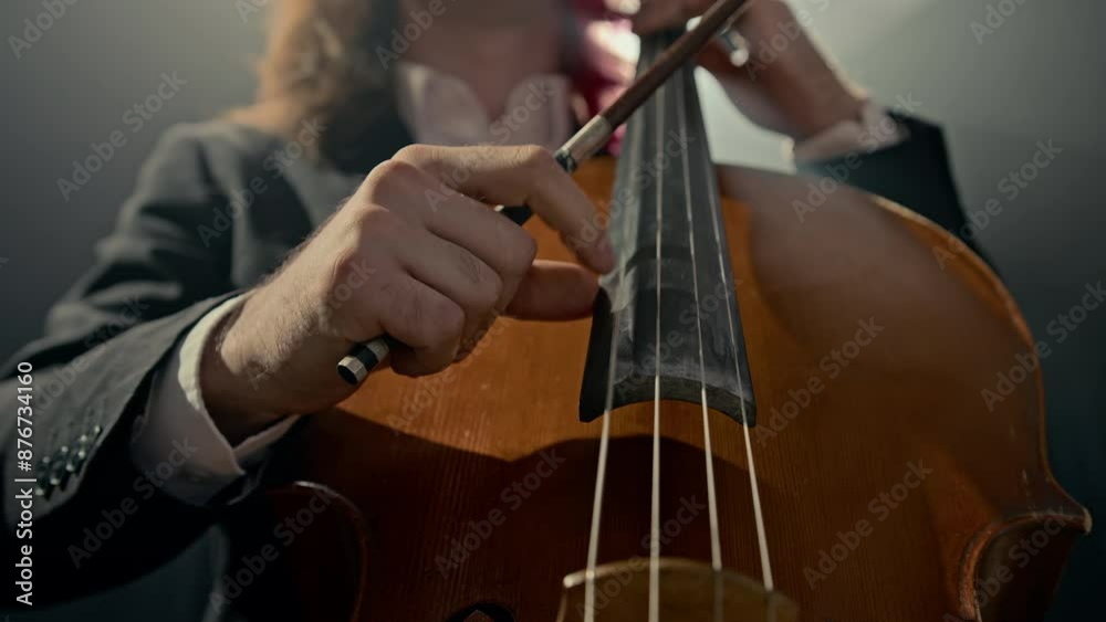 Cropped shot of talented male music performer playing cello professionally on dark background Cropped shot of talented male music performer playing cello professionally on dark background