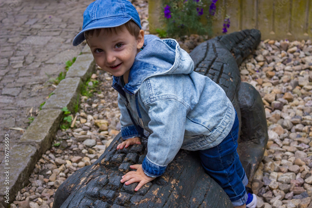 A little toddler in jeans has fun watching the animals at a modern urban zoo