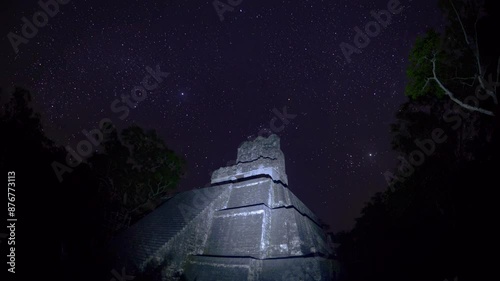 night lapse captures the majestic beauty of a star-filled sky above an ancient stone structure, surrounded by silhouettes of trees. photo