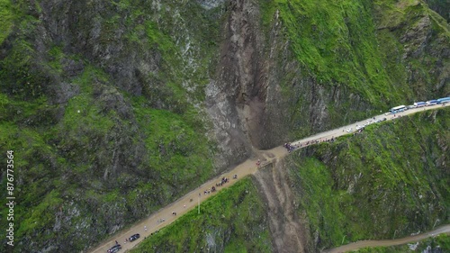 Aerial view of landslide (huaico) blocking a highway through steep hills in Lima, Peru. Drone footage moves left to right focusing on landslide, showing halted traffic unable to pass the closed road. photo