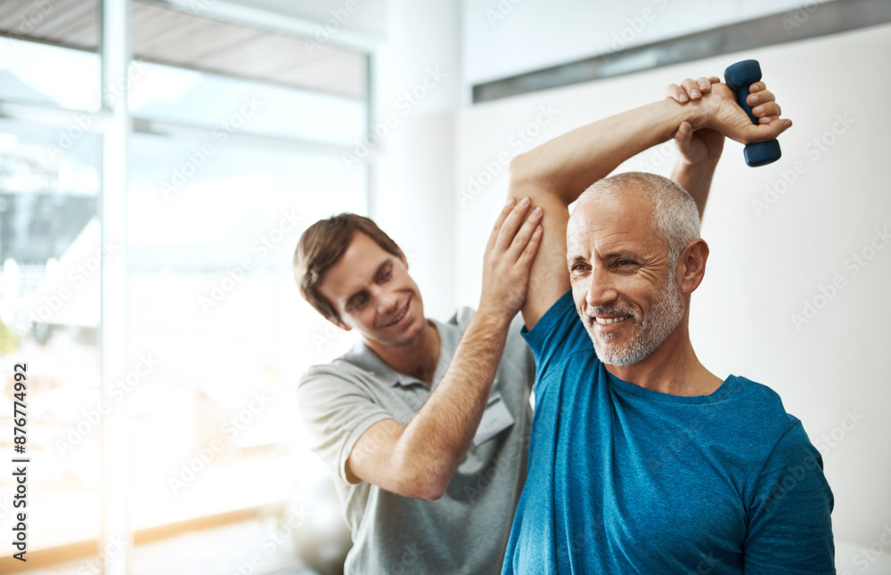 Obraz premium Strength, physiotherapist and mature man with dumbbell in clinic for physical therapy, support or mobility exercise. Fitness, health worker and patient for help, stretching arms or rehabilitation