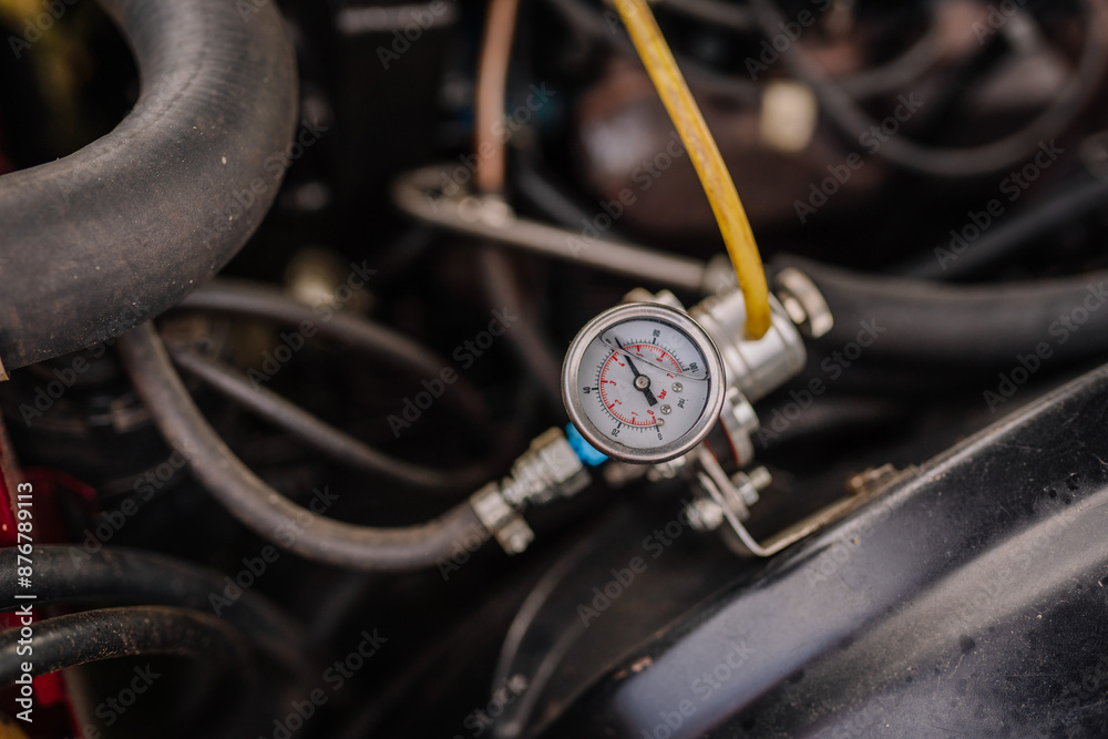 Fototapeta premium limbazi, Latvia, June 29, 2024 - Close-up of a car engine's pressure gauge with hoses and wiring visible, showcasing mechanical details and functionality. Some copy space...