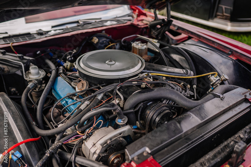 Close-up of a car engine with various components, hoses, and wires, showcasing mechanical details and complexity. Some copy space.