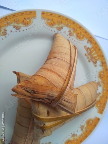 Lepet or leupeut Indonesian traditional food with glutinous rice and grated coconut ingredients wrapped in coconut leaves isolated on white background photo