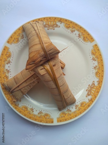 Lepet or leupeut Indonesian traditional food with glutinous rice and grated coconut ingredients wrapped in coconut leaves isolated on white background photo