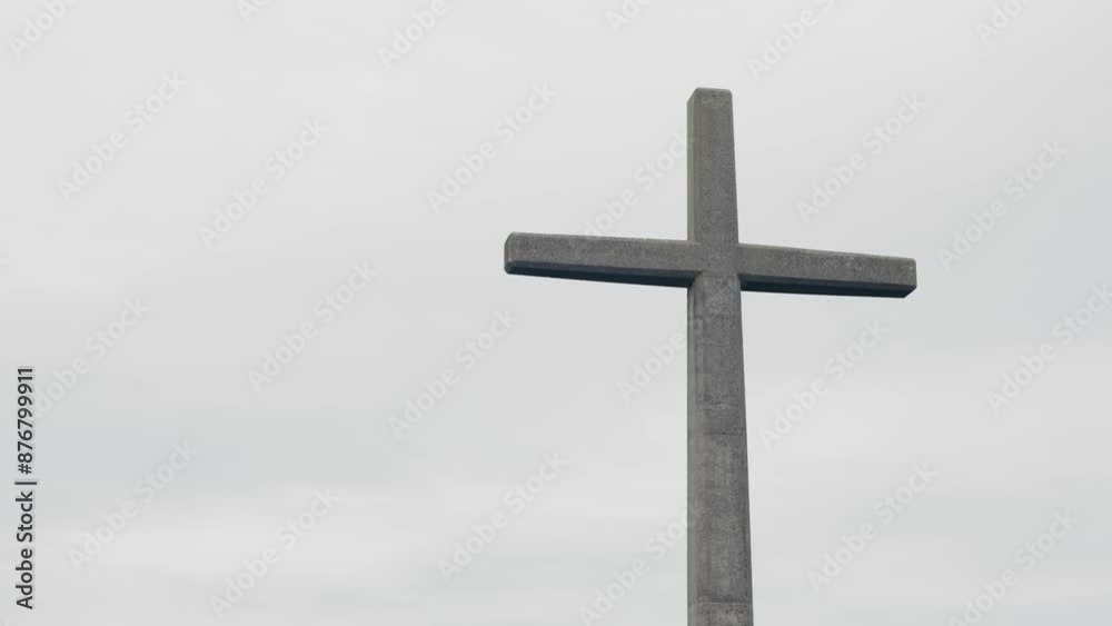 A large stone cross stands tall against a cloudy sky in Portugal, symbolizing faith and spirituality. Stone Cross Against Grey Sky Symbolizing Faith and Religion A large stone cross stands tall against a cloudy sky in Portugal, symbolizing faith and spirituality. Stone Cross Against Grey Sky Symbolizing Faith and Religion