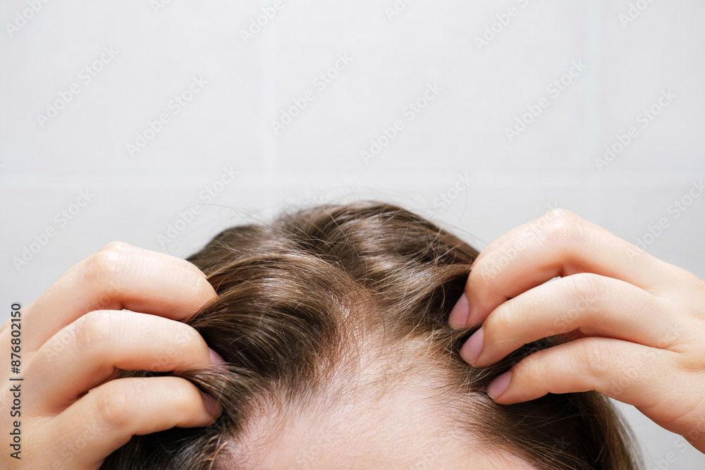 Fototapeta premium Woman touching her hair close-up on gray tiles background, hair loss concept.