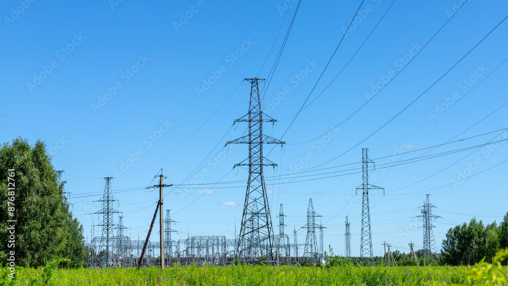 Power lines in a green field in the sunny summer day. Electrical substation.