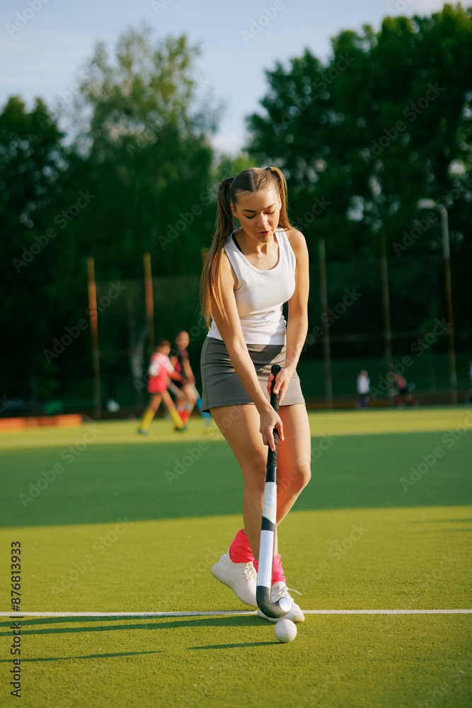 Fototapeta premium girl hockey player plays field hockey on a sunny day, the hockey player hits the ball with a stick