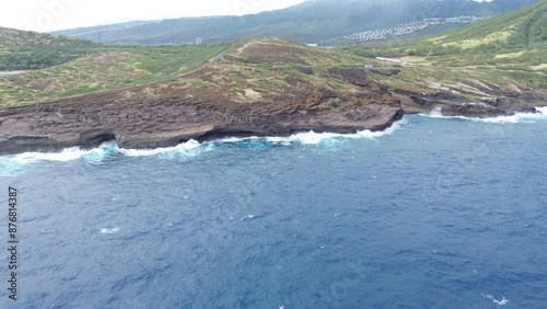 Flying over Rugged Coastal Landscape with Crashing Waves and Green Hills