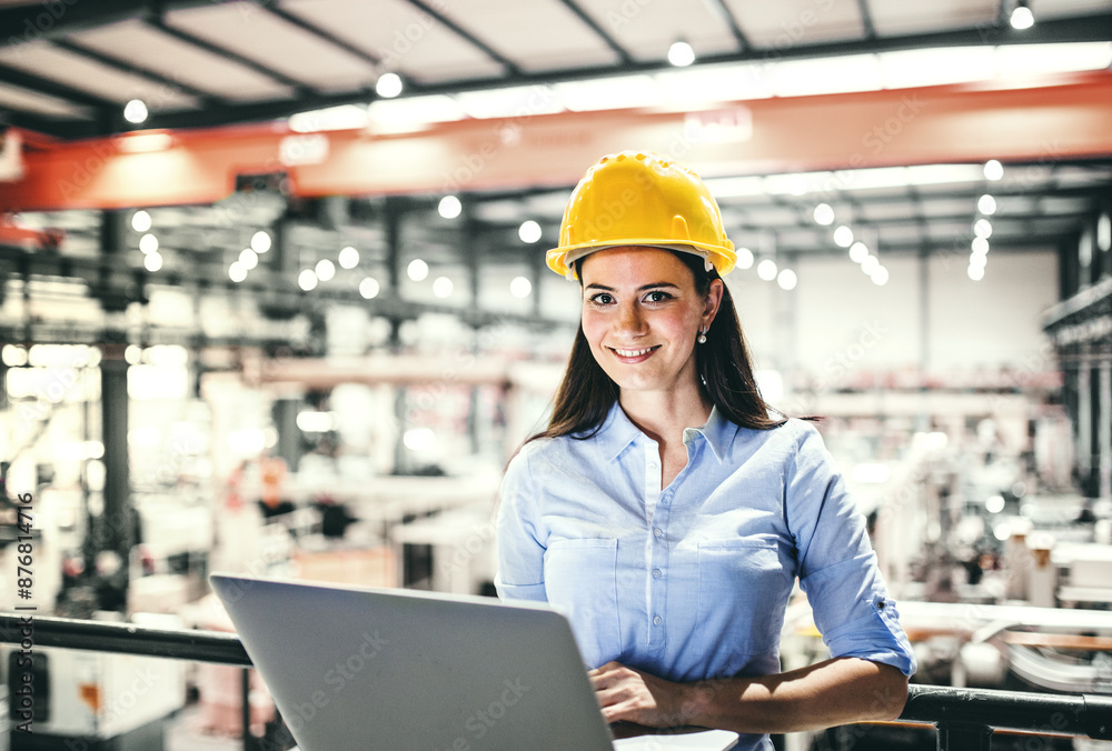 Female project manager standing in modern industrial factory, holding notebook Manufacturing facility with robotics, robotic arms and automation. Storing products and materials in warehouse.
