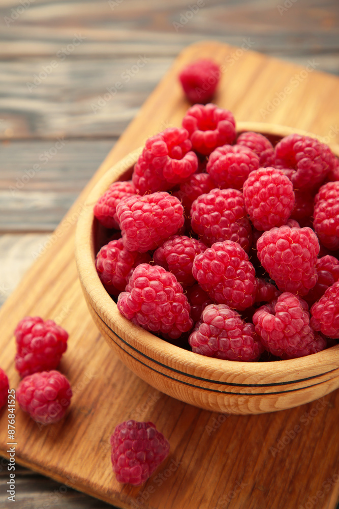 Raspberries in wooden bowl on brown background. Vertical photo Raspberries in wooden bowl on brown background. Vertical photo