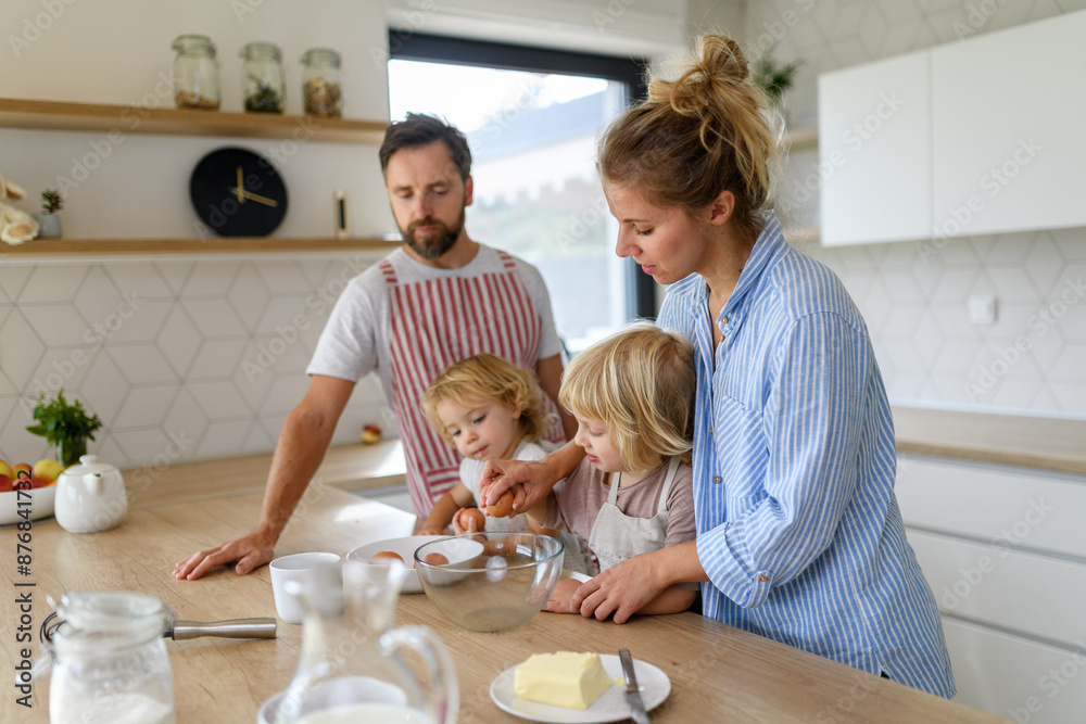 Young nuclear family making pancakes together. Parents and children in kitchen, preparing pancake batter, spending weekend day indoors. Young nuclear family making pancakes together. Parents and children in kitchen, preparing pancake batter, spending weekend day indoors.