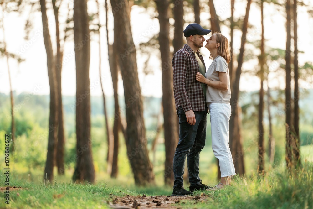 Looking at each other. Lovely couple are together in the forest at summer daytime Looking at each other. Lovely couple are together in the forest at summer daytime