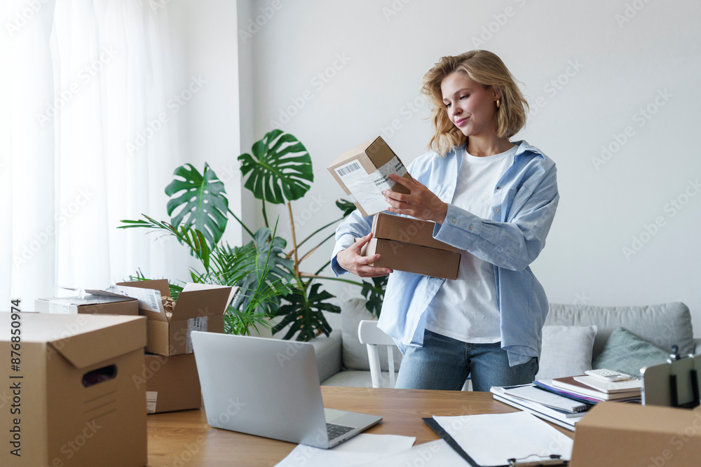 Freelancer reading details on delivery boxes standing at home office Freelancer reading details on delivery boxes standing at home office