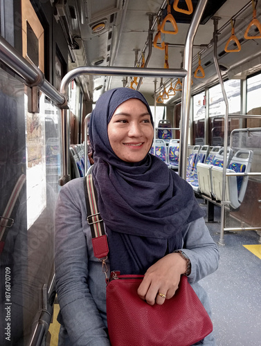 Vertical Photo Of Young Asian Muslim Woman Traveling With Public Transport Sitting Relaxed