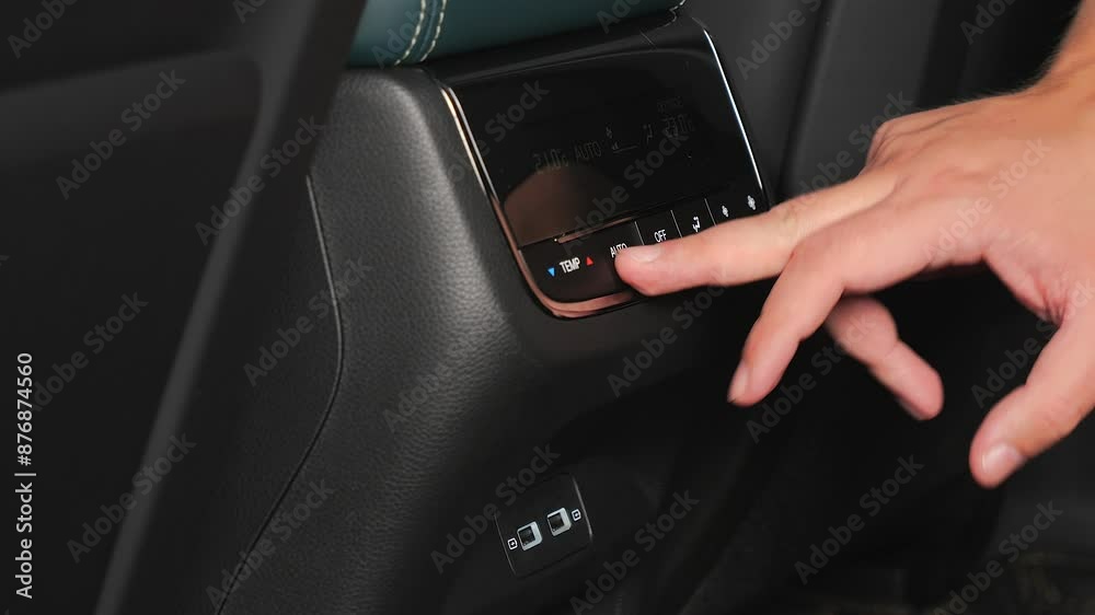 A hand presses the rear climate control buttons A hand presses the rear climate control buttons