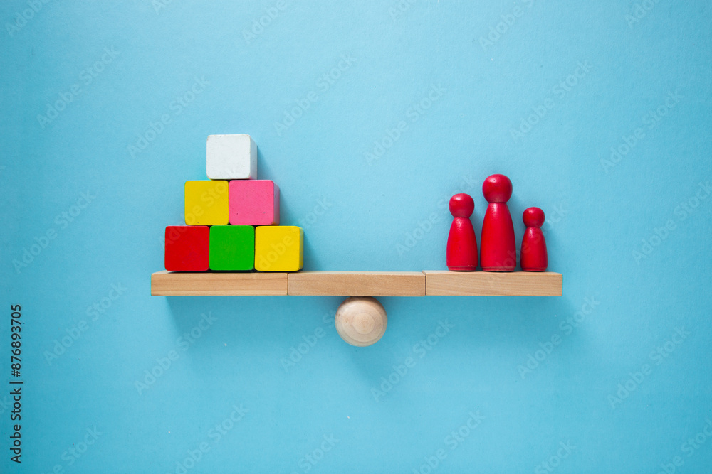 Wooden scale balancing stacked cubes and family on blue background Wooden scale balancing stacked cubes and family on blue background