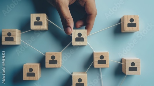 hand placing wooden blocks with icons of people on a blue background, forming a network pattern