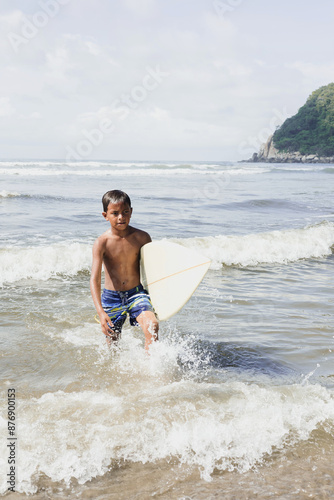 Photography latin child boy with surfboard on the beach in Mexico Latin America, hispanic pe