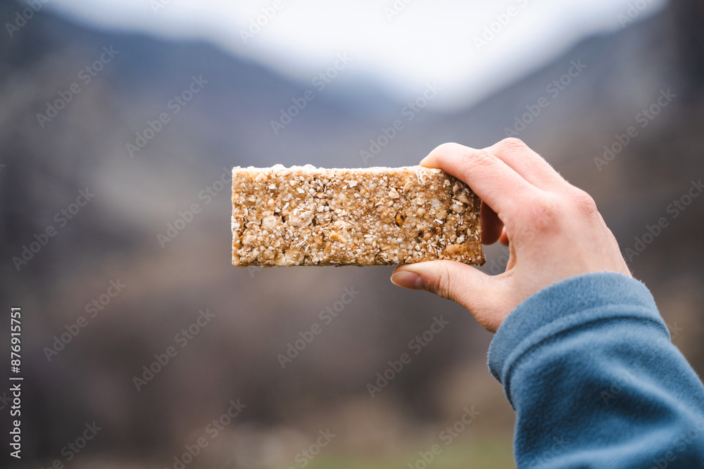 © Соня Монштейн - Close up of female hand holding grain cereal bar snack on the hike, dessert, muesli, healthy food, hiking, tourism, sports, active, outdoor lifestyle © Соня Монштейн - Close up of female hand holding grain cereal bar snack on the hike, dessert, muesli, healthy food, hiking, tourism, sports, active, outdoor lifestyle
