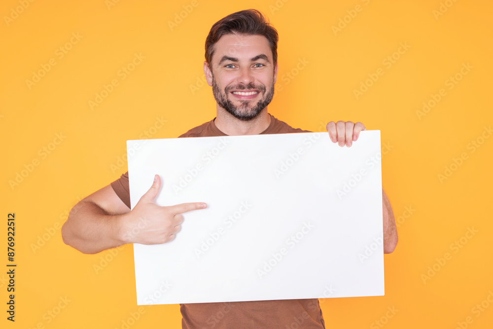 Happy man with blank banner isolated on studio background. Portrait of attractive man with empty blank poster. Man showing poster, pointing finger on signboard placard. Billboard or banner concept. Happy man with blank banner isolated on studio background. Portrait of attractive man with empty blank poster. Man showing poster, pointing finger on signboard placard. Billboard or banner concept.