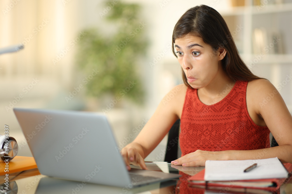 Perplexed student checking laptop at home Perplexed student checking laptop at home