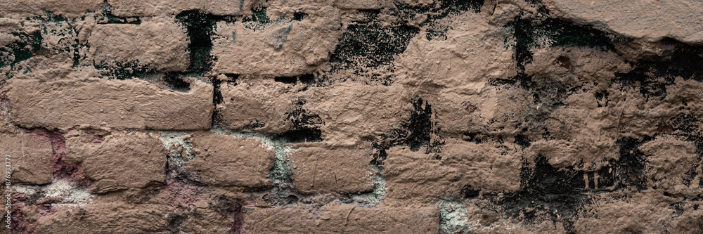 Old brick wall with peeling stucco. Weathered rough wall surface with brickwork. The wall is painted in different colors. Wide panoramic texture for background and design. Old brick wall with peeling stucco. Weathered rough wall surface with brickwork. The wall is painted in different colors. Wide panoramic texture for background and design.