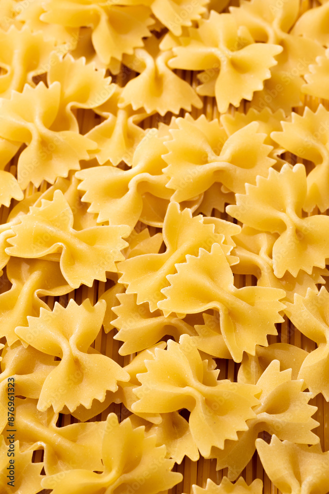 Dry golden pasta farfalle or bow tie. Background texture of raw pasta Dry golden pasta farfalle or bow tie. Background texture of raw pasta