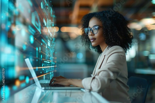 Beautiful African American businesswoman with futuristic holographic screens displaying AI financial data while banking online on a laptop in a high-tech office.