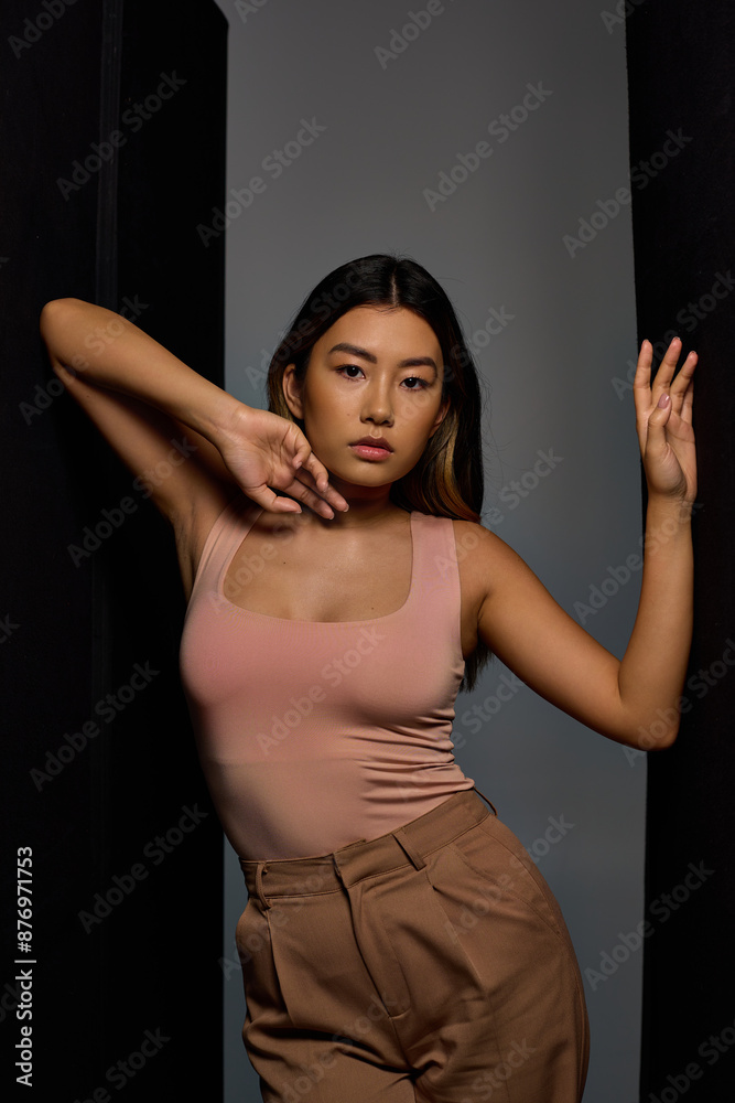 A stylishly dressed woman stands by a wall, her arms gracefully outstretched. A stylishly dressed woman stands by a wall, her arms gracefully outstretched.