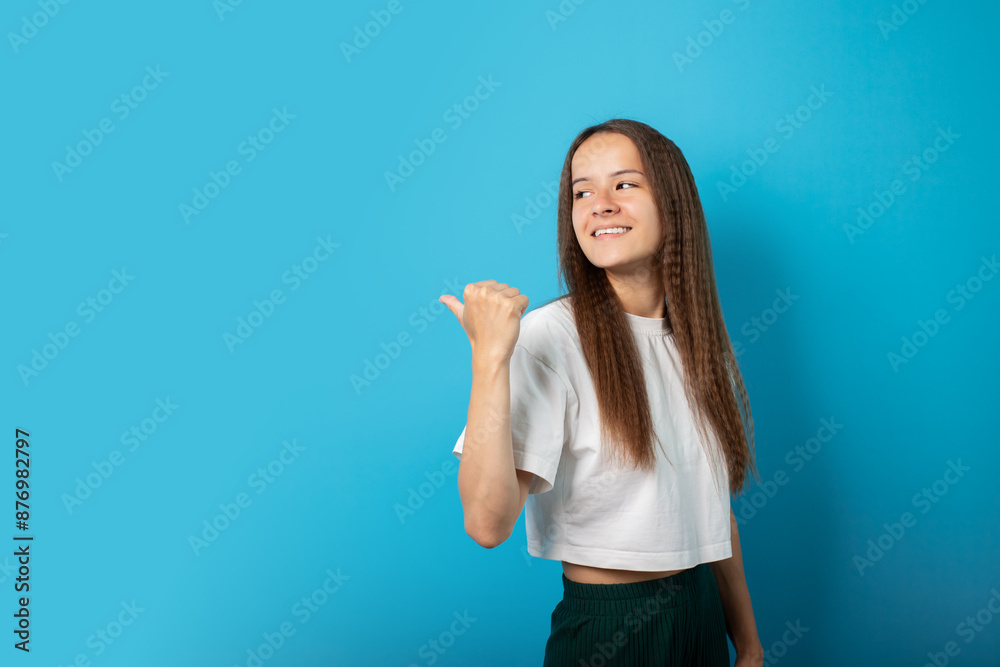 Teenager points to an empty space for text, copy space, portrait on blue background, young cute emotional student, pretty girl with a smile, emotional teen in a stylish shirt, joyful and happy Teenager points to an empty space for text, copy space, portrait on blue background, young cute emotional student, pretty girl with a smile, emotional teen in a stylish shirt, joyful and happy
