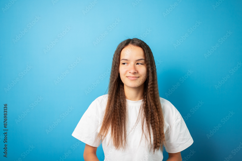 Teenager portrait on blue background, young cute emotional student, curly hair teen posing in studio Teenager portrait on blue background, young cute emotional student, curly hair teen posing in studio