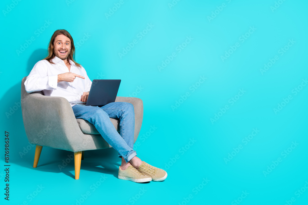 Full length photo of cheerful positive guy dressed white shirt showing finger modern device emtpy space isolated turquoise color background Full length photo of cheerful positive guy dressed white shirt showing finger modern device emtpy space isolated turquoise color background