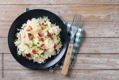 Slovak potato dumplings halusky with steamed sauerkraut and bacon on wooden table. Top view. Copy space photo