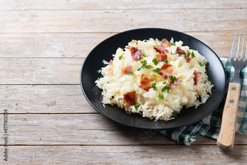 Slovak potato dumplings halusky with steamed sauerkraut and bacon on wooden table. Copy space photo